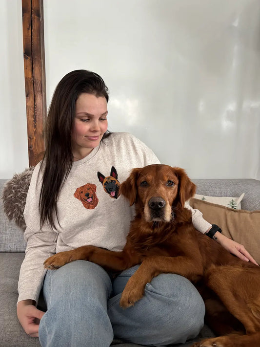 Hundeeier i genser med personlig hundebroderi, sammen med hunden i sofaen